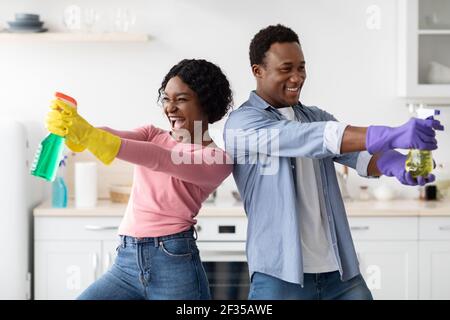 Homme et femme afro-américains espiègle avec des pulvérisateurs Banque D'Images