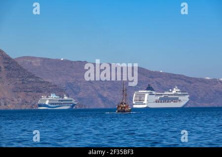 Grèce. Journée ensoleillée au large de la côte de Santorin. Deux navires de croisière à plusieurs ponts et un ancien navire à trois mâts Banque D'Images