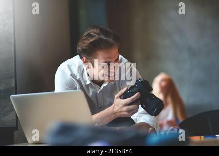 Les affaires, les startups et le concept des gens : un photographe, un concepteur, un travailleur de bureau homme créatif et heureux qui vérifie les vidéos sur son appareil photo. Banque D'Images