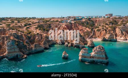 Une vue aérienne d'une mer bleue magnifique et des bâtiments au sommet des falaises côtières de l'Algarve, Portugal Banque D'Images