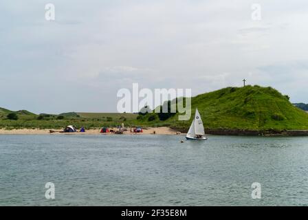 Un canot pneumatique Wayfarer navigue au-delà de St Cuthberts Cross sur Church Hill tandis que les gens campent sur la plage, Alnmouth, village côtier, Northumberland, Angleterre, Banque D'Images