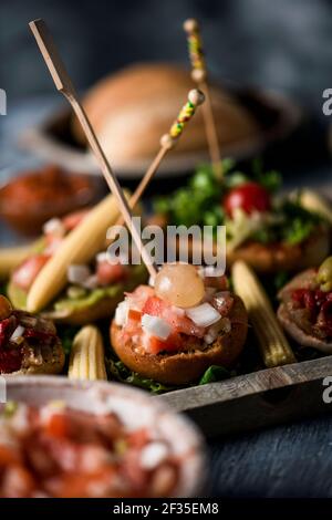 gros plan de quelques pinchos vegan espagnols différents, faits avec du pain avec différentes garnitures, et nappés de brochettes, servis comme encas ou hors-d'œuvre sur un Banque D'Images