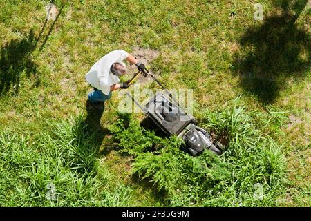 L'homme s'occupe de la pelouse. Vue de dessus. Un homme tond la pelouse avec une tondeuse Banque D'Images