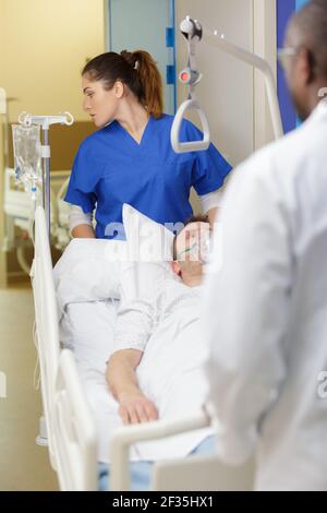 infirmière masculine poussant le lit de civière dans le couloir de l'hôpital Banque D'Images