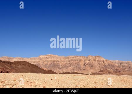 Paysage désertique du désert de Negev dans le parc Timna, Israël. Les couleurs brunâtres et les nuances de rochers contrastent avec le ciel bleu clair avec beaucoup d'espace de copie. Banque D'Images
