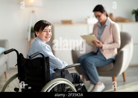 Portrait d'un adolescent handicapé heureux en fauteuil roulant regardant l'appareil photo et souriant, espace de copie Banque D'Images