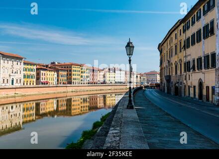 Lampe historique de la rue lumière de la rive de la rivière Arno, Pise, Italie. Rangée de bâtiments réfléchie sur la surface de l'eau. Banque D'Images