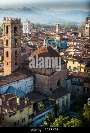 Maisons en briques rouges et tuiles rouges dans le panorama de la ville de Lucca, Italie. Grande tour à côté du bâtiment carré en forme de dôme. Arrière-plan de l'architecture. Banque D'Images