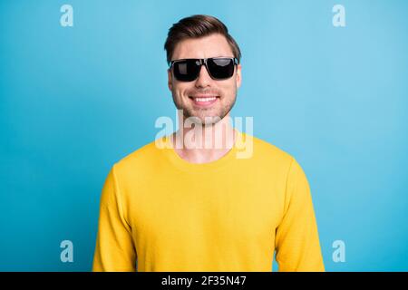 Photo d'une jeune personne satisfaite porter un verre de soleil look appareil photo en dents de œil sourire isolé sur fond bleu Banque D'Images