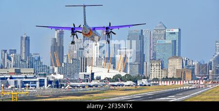 Avion turbopropulseur Flybe débarquant sur la piste d'atterrissage de l'aéroport de London City Newham O2 arena & Canary Wharf Londres Docklands Skyline au-delà de Tower Hamlets Angleterre Royaume-Uni Banque D'Images