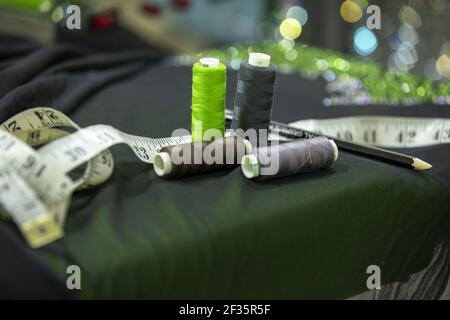Outils de couture. Rouleaux de fil à coudre, centimètre, ciseaux, tarauds sur tissu noir Banque D'Images