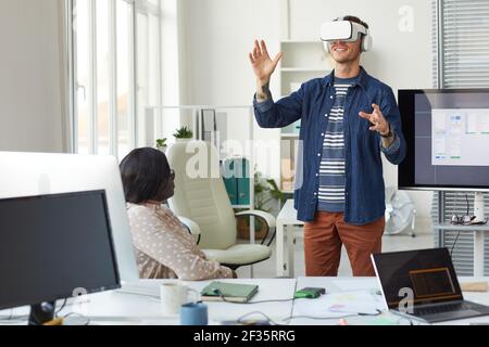 Portrait de l'équipe DE développement INFORMATIQUE qui conçoit un logiciel de réalité immersive en mettant l'accent sur l'homme portant un casque VR au bureau, dans un espace de copie Banque D'Images