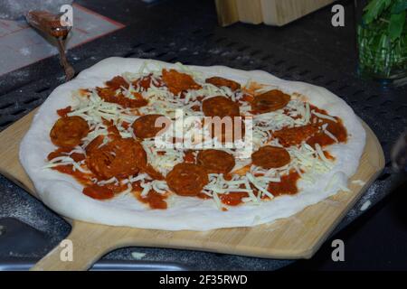vue rapprochée de la pizza épicée au salami avant de la cuire sur du bois carte Banque D'Images