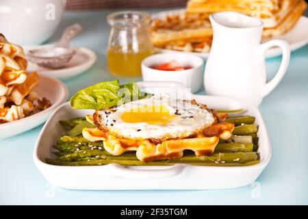 Petit-déjeuner le matin. Gaufres fraîches maison avec omelette, feuilles d'épinards et asperges Banque D'Images