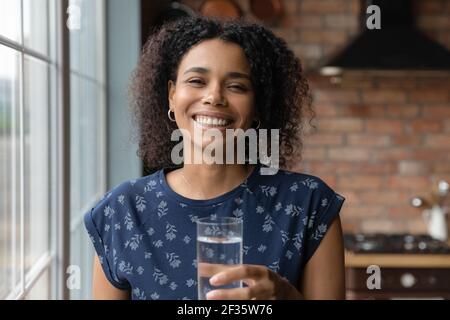Portrait d'une jeune femme africaine souriante tenant un verre d'eau Banque D'Images
