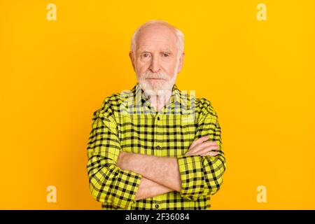 Photo d'un vieil homme sérieux et mûr, mains croisées, aspect grincheux appareil photo porter un tissu écossais vert chemise isolé couleur jaune arrière-plan Banque D'Images