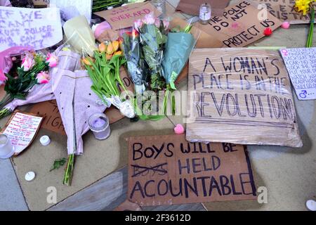 Des placardes qui font pression pour la sécurité des femmes et des fleurs à la statue d'Emmeline Pankhurst sur la place Saint-Pierre, Manchester, Angleterre, Royaume-Uni, sont partis après la vigile à la mémoire de Sarah Everard le 13 mars 2021. Un policier de la région métropolitaine de Londres a été inculpé d'enlèvement et de meurtre de Sarah Everard le 12 mars. Il a comparu devant le tribunal des magistrats de Westminster le 13 mars et a été remis en garde à vue pour comparaître devant le tribunal Old Bailey le 16 mars. Emmeline Pankhurst était le chef du mouvement des suffragettes au Royaume-Uni. La statue de bronze a été sculptée par Hazel Reeves. Banque D'Images