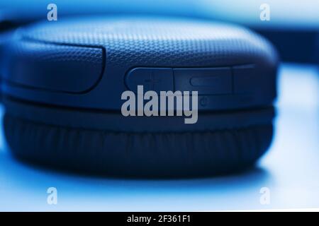 Casque sans fil avec boutons sur fond bleu. Vue en gros plan. Concept de musique. Faible profondeur de champ Banque D'Images