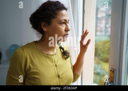 Femme noire inquiète en regardant par la fenêtre