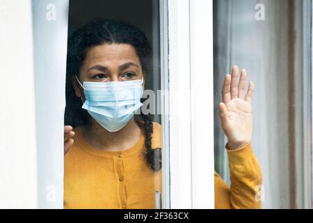 Femme noire inquiète en regardant par la fenêtre