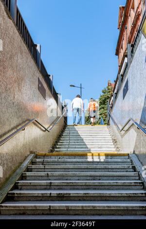 Un homme et une femme émergeant de la lumière du soleil depuis les marches du métro, Londres, Royaume-Uni Banque D'Images