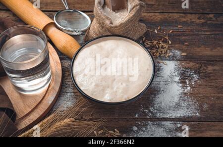 Levain, farine, eau sur fond marron. Pâte à levure. Le concept de fabrication du pain. Banque D'Images