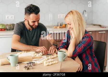 Un jeune couple amoureux de petit ami et de petite amie souriante prépare des produits de boulangerie. Banque D'Images