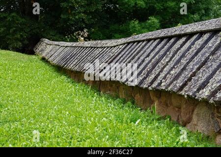 Haie en pierre ancienne avec un toit de planches de mousse grise. Banque D'Images
