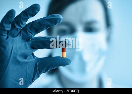 Femme avec masque de protection tenir la pilule médicale à la main Banque D'Images