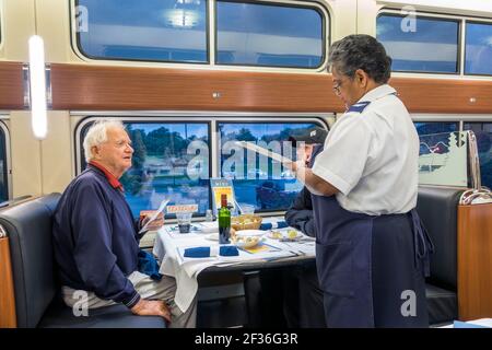 Washington DC, train de passagers Amtrak Silver Meteor Star, service de dîner de voiture de restaurant homme senior, serveur de femme noire prenant l'ordre d'écriture intérieur Banque D'Images