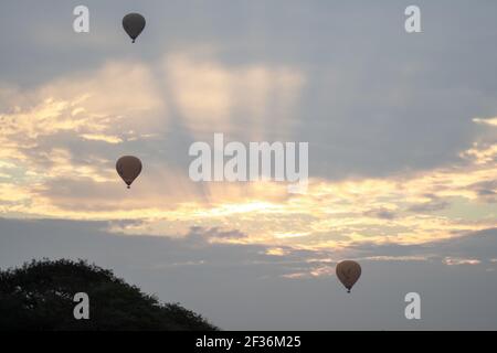 BAGAN, NYAUNG-U, MYANMAR - 2 JANVIER 2020 : trois ballons à air chaud dans le ciel au lever du soleil tôt le matin, par une journée nuageux Banque D'Images