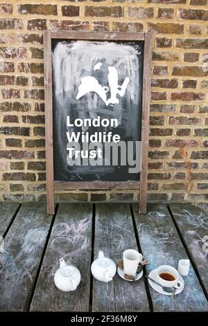 London Wildlife Trust écrit sur un tableau noir à l'extérieur de Coal House Café avec vaisselle - théières et tasses en face de Woodberry Terres humides Stoke Newington L. Banque D'Images