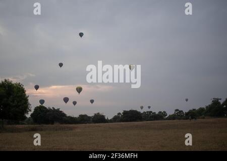 BAGAN, NYAUNG-U, MYANMAR - 2 JANVIER 2020: Deux touristes regarde les ballons à air chaud dans le ciel en début de matinée, un jour nuageux depuis un champ Banque D'Images