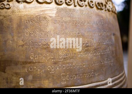 BAGAN, NYAUNG-U, MYANMAR - 2 JANVIER 2020 : gros plan du texte birman sur une grande cloche bouddhiste massive par un temple pagode historique Banque D'Images