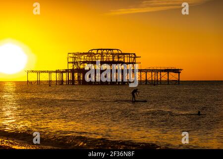 Un membre du paddle-board public dans la mer à côté de l'abandonné West Pier à Brighton, East Sussex Banque D'Images