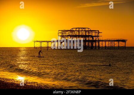 Un membre du paddle-board public dans la mer à côté de l'abandonné West Pier à Brighton, East Sussex Banque D'Images