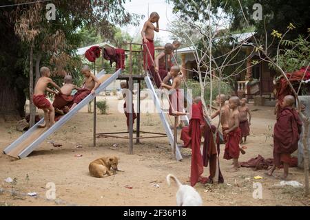 BAGAN, NYAUNG-U, MYANMAR - 2 JANVIER 2020 : des jeunes moines jouent, coutent, sautent, grimpent, rient et s'amusent ensemble dans un terrain de jeu local avec un toboggan Banque D'Images