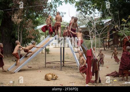 BAGAN, NYAUNG-U, MYANMAR - 2 JANVIER 2020 : des jeunes moines jouent, coutent, sautent, grimpent, rient et s'amusent ensemble dans un terrain de jeu local avec un toboggan Banque D'Images