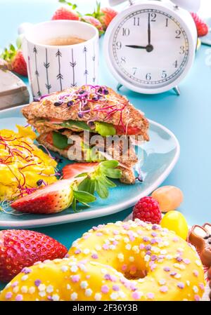 Super nourriture pour le petit déjeuner et beignets sucrés pain grillé avec du jambon, de la salade et de la brouille, arrosé de graines germées, une assiette de céréales avec des baies, de la super nourriture. Délicieux petit déjeuner sain Banque D'Images