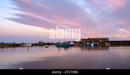 Lyme Regis, Dorset, Royaume-Uni. 15 mars 2021. Météo au Royaume-Uni: Le ciel du soir au-dessus du port de Cobb à Lyme Regis brille avec des teintes roses et lilas peu après le coucher du soleil. Credit: Celia McMahon/Alamy Live News. Banque D'Images