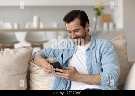 Sourire homme caucasien utiliser smartphone SMS en ligne Banque D'Images