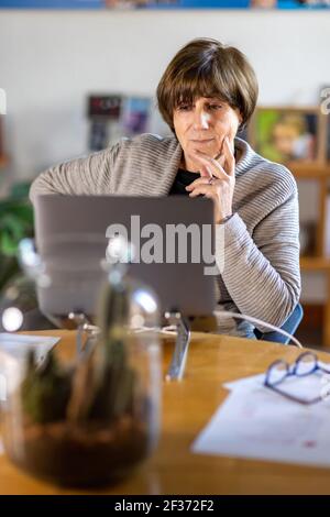 Psychologue âgé et consultant senior travaillant à distance depuis la maison pendant une réunion vidéo avec son ordinateur portable pendant la quarantaine ou le verrouillage Banque D'Images