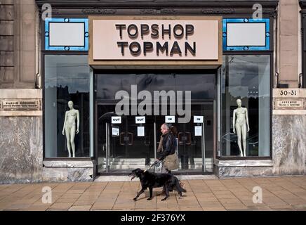 Homme marchant son chien après l'entrée du magasin Topshop Topman sur Princes Street, Édimbourg, Écosse, Royaume-Uni. Fait partie du groupe Arcadia en échec. Banque D'Images
