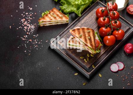 Délicieux sandwich avec toasts croquants, jambon, laitue et tomates. Petit déjeuner nourrissant rapide Banque D'Images