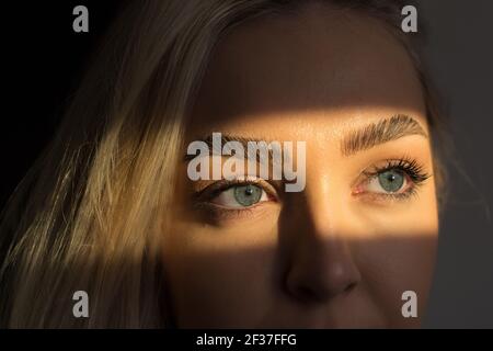 Gros plan avec les yeux bleus d'une femme regardant dehors la fenêtre dans le Banque D'Images