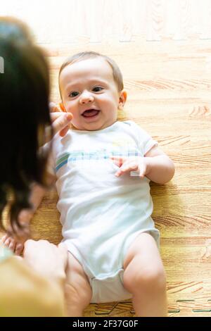 bébé souriant regardant sa mère couché sur le sol. Banque D'Images