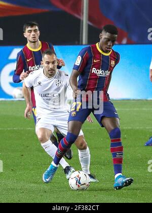 Barcelone. 16 mars 2021. Ilaix Moriba (R) de Barcelone vies avec David Ferreiro de Huesca pendant le match de football de la Ligue espagnole entre Barcelone et SD Huesca à Barcelone, Espagne, le 15 mars 2021. Credit: Xinhua/Alay Live News Banque D'Images