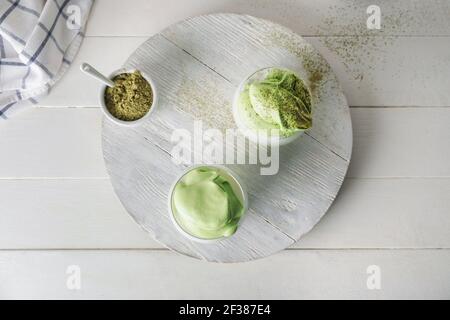 Plateau avec des verres de délicieux latte de matcha de Dalgona et de poudre sur fond en bois clair Banque D'Images