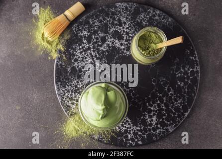 Composition avec délicieux Dalgona matcha latte sur fond sombre Banque D'Images