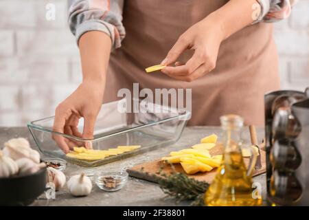 Femme cuisant des pommes de terre dans la cuisine Banque D'Images